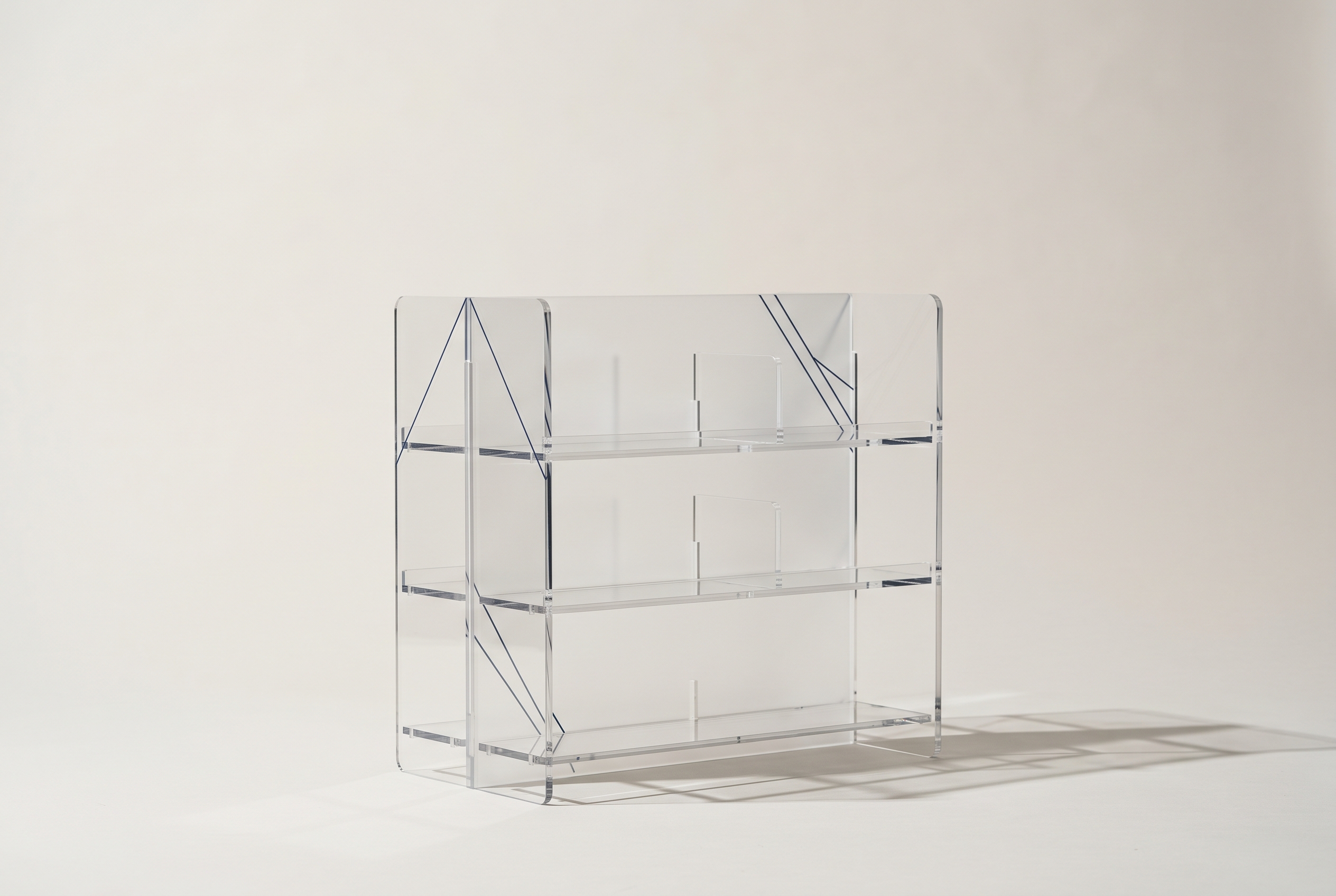 A minimalist acrylic retail display fixture with precise laser-cut edges, photographed in a studio setting